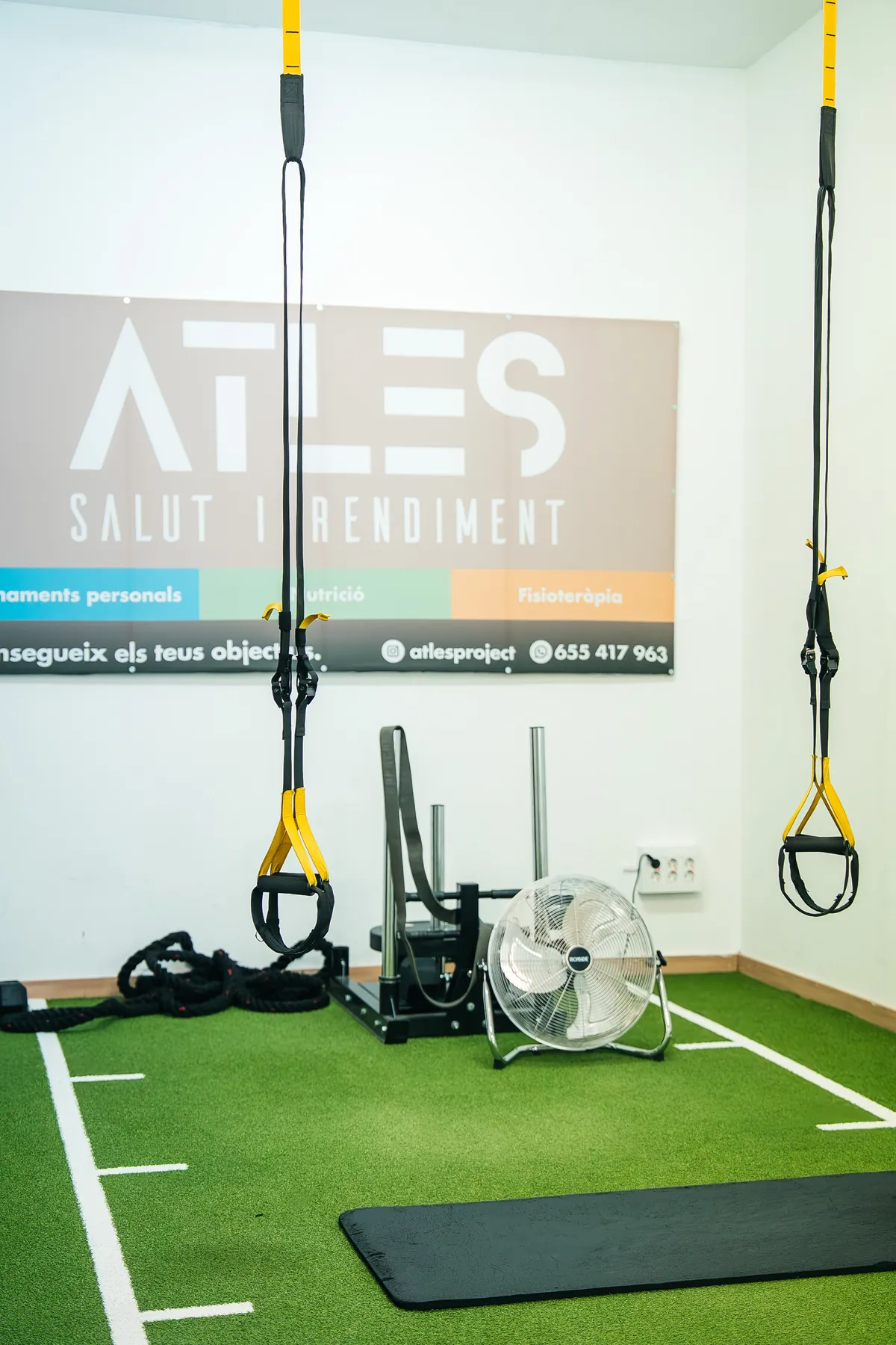 Zona d’entrenament d’Atles amb cintes de suspensió, gespa i estora